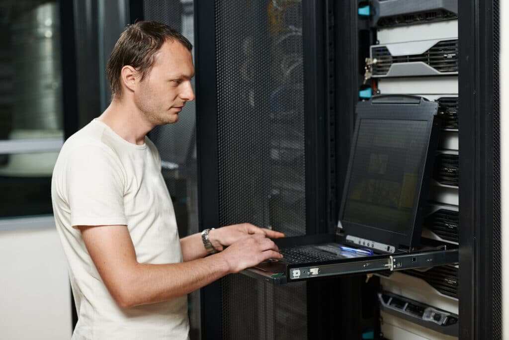 Mann arbeitet mit Laptop am Server, Serverraum, Storage