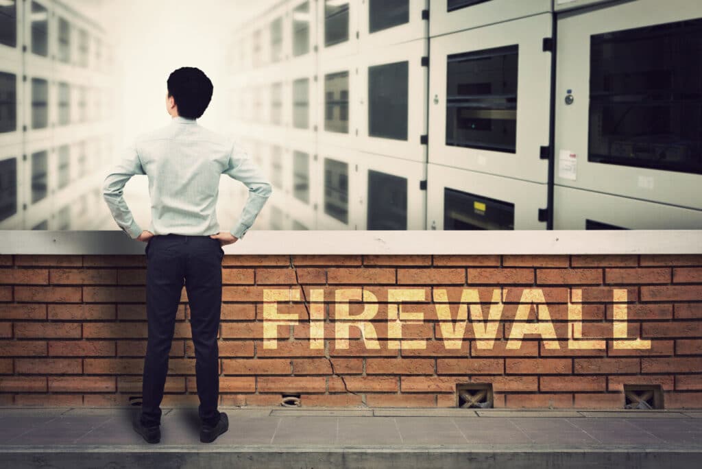 Mann mit Rücken und Mauer mit Schrift Firewall, Firewall-Lösungen, IT-Sicherheit, Firewall Management