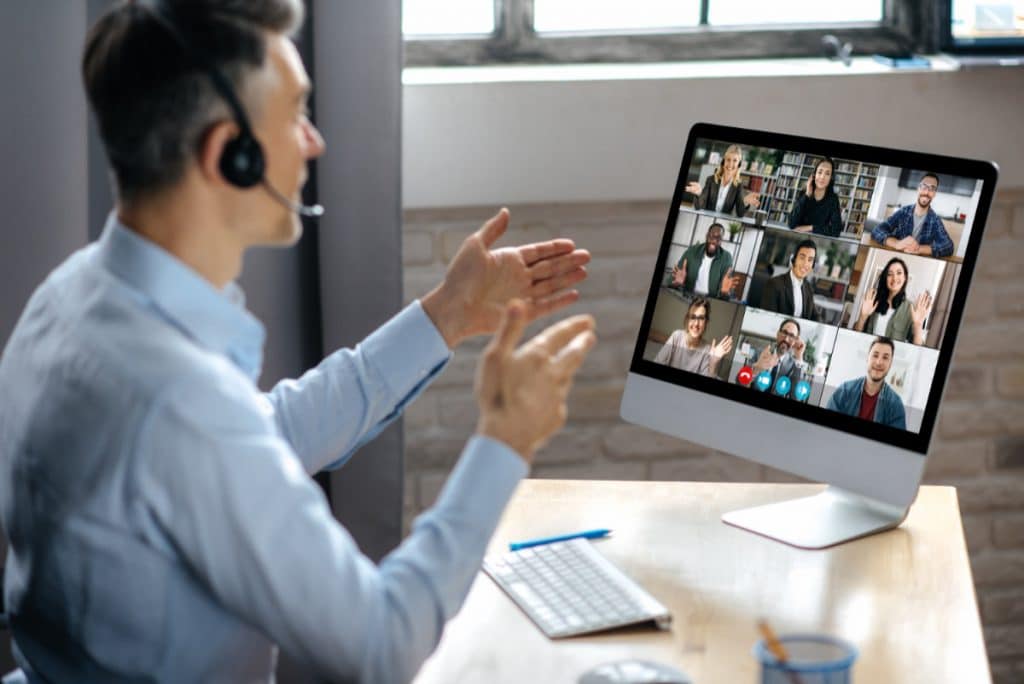 Kommunikation, virtuelle kommunikation, teams, videokonferenz, Virtual business meeting online. Successful businessman is negotiating with multiracial business partners on a video conference using a computer while sitting at his workplace